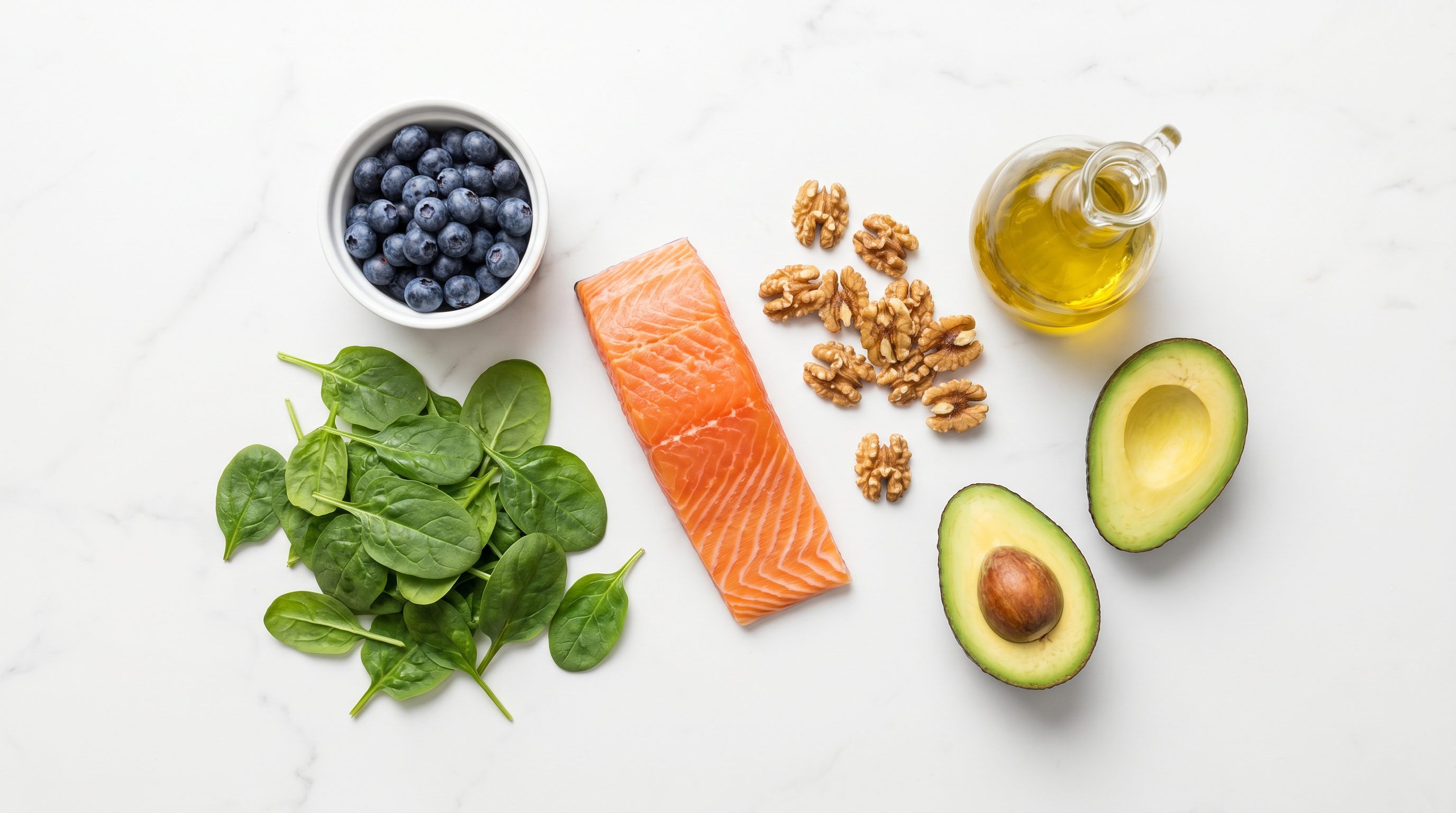 Mediterranean diet foods for liver health: olive oil, salmon, leafy greens, legumes, and whole grains on a clean white surface